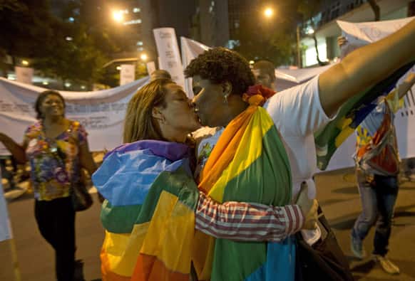 People wearing gay pride flags kiss during a protest against homophobia in Rio de Janeiro, Brazil.