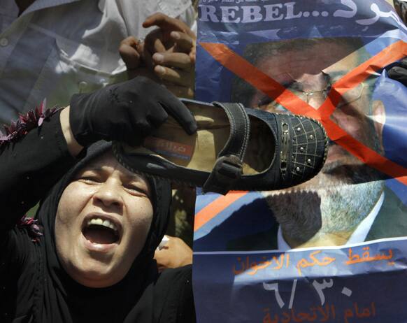 An Egyptian protester hits a poster depicting President Mohammed Morsi in Tahrir Square, the focal point of Egyptian uprising, in Cairo.