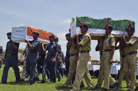 Security officers carry coffins containing victims of a helicopter that crashed during a rescue mission in flood-ravaged northern India, in Dehradun.
