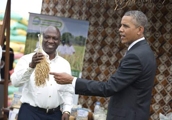 Salif Romano Niang, co-founder of Malo, a company that helps farmers earn a living wage, shows US President Barack Obama a crop of his rice during a food security expo in Dakar, Senegal.