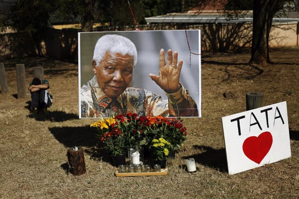 A young boy rests by a large picture of former South African President Nelson Mandela placed by the Union Building in Pretoria, South Africa.
