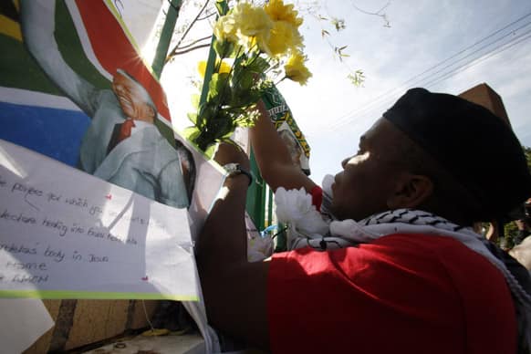 A member of the ruling party youth league, places flowers outside the Mediclinic Heart Hospital where former South African President Nelson Mandela is being treated in Pretoria, South Africa.