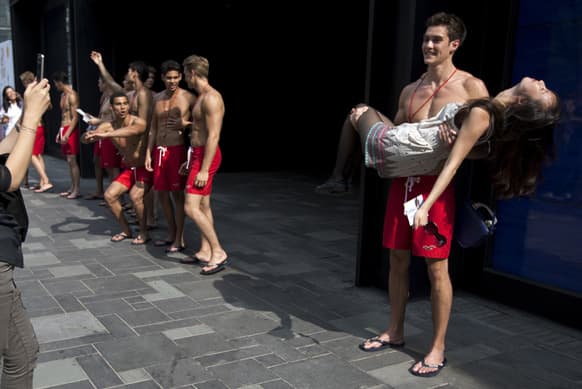 A Chinese women acts fainted as she poses a photo session with a lifeguard model outside the new Hollister Co. clothing store, which to open on June 29, during a promotion event at a commercial district in Beijing, China.