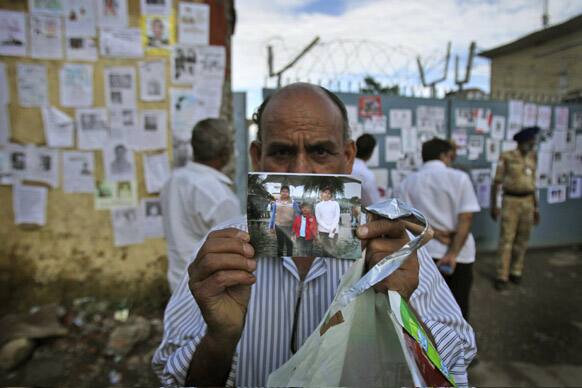A man shows a photo of his family members who went missing during monsoon flooding near the airport gate in Jollygrant, in northern Indian state of Uttarakhand.