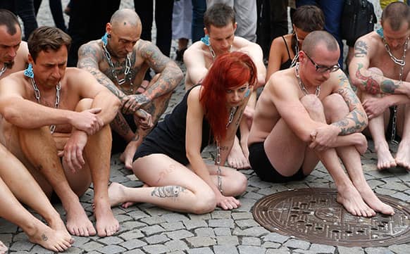 Animal rights activists sit in a enclosure after being branded with number 269 in Prague, Czech Republic.