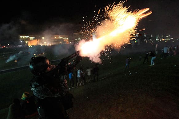 A military policeman fires tear gas at demonstrators during an anti-government protest in downtown Brasilia, Brazil.