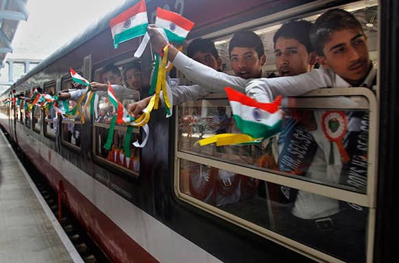 Young Indian school children displaythe national flag as they wave from inside the first train connecting Qazigund to Banihal during its inauguration, in Banihal some 120 kilometers (75 miles) south of Srinagar.