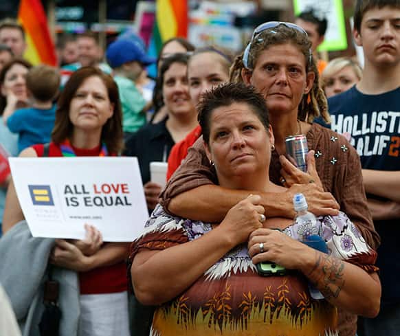 Jennifer Bryce, foreground, and her partner Renee Hendricks listen to speakers during a rally in the Boystown neighborhood of Chicago.