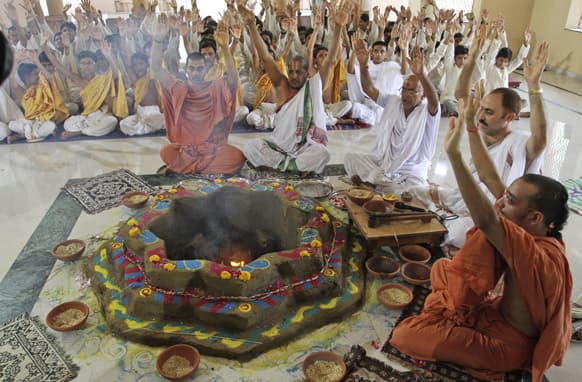 students of Swaminarayan Gurukul Vishwavidhya Pratishthanam (SGVP) along with saints raise their hands as they perform rituals during a “yagya,” or a fire ritual, to pray for the Uttarakhand flood victims, in Ahmadabad.