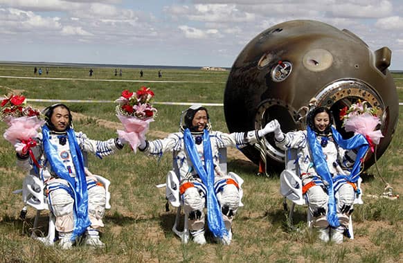Chinese astronauts, from left, Zhang Xiaoguang, Nie Haisheng and Wang Yaping celebrate after getting out of the re-entry capsule of China`s Shenzhou 10 spacecraft following its successful landing at the main landing site in Siziwang Banner, north China`s Inner Mongolia Autonomous Region.