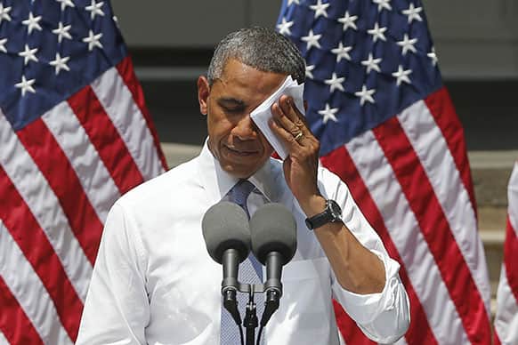 President Barack Obama wipes his face as he speaks about climate change, at Georgetown University in Washington.