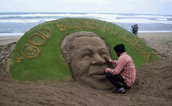 Sudarshan Pattnaik gives finishing touches to a sand sculpture of former South African President Nelson Mandela with a message, at a beach in Puri.