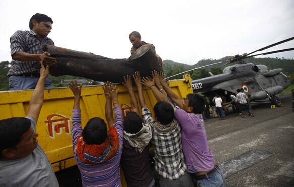 Locals unload a large piece of wood from a truck to be placed on to an Indian Air force helicopter as cremation efforts for those killed in landslides and monsoon floods are underway, in Gauchar, in Uttarakhand.