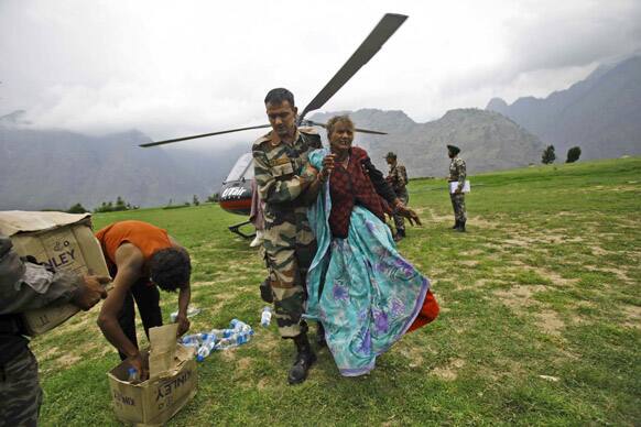 An Indian army soldier helps an injured pilgrim after she was rescued from the higher reaches of mountains, at a makeshift helipad at Joshimath in Uttarakhand.