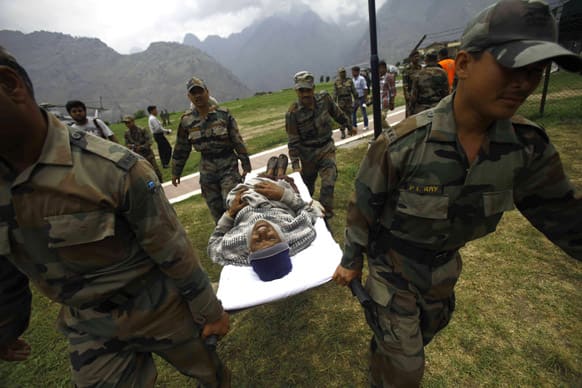An injured pilgrim cries in a pain as Indian army soldiers carry him on a stretcher after he was rescued from the higher reaches of mountains at a makeshift helipad at Joshimath, Uttarakhand.