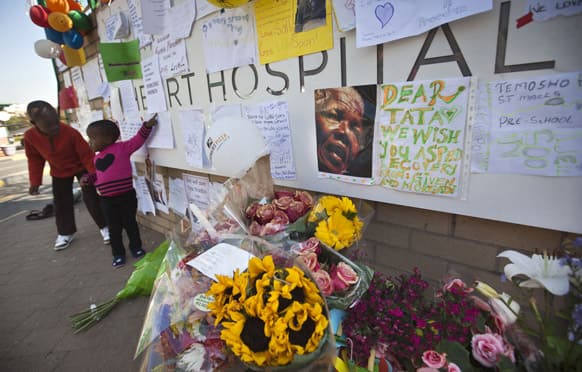 Otsile Maenetja, 3, and her brother Orapeleng Maenetja, 9, look at some of the other get-well cards left after leaving their own, at the entrance to the Mediclinic Heart Hospital where former South African President Nelson Mandela is being treated in Pretoria, South Africa.