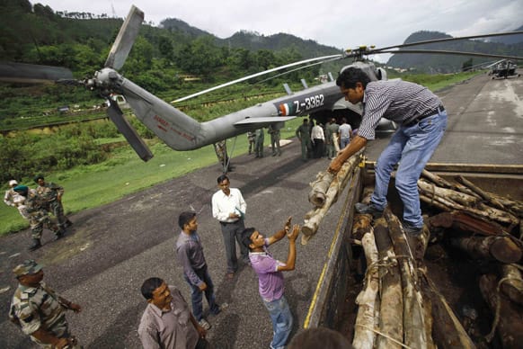 Locals unload woods from a truck to be loaded on to an Indian Air force helicopter, in Gauchar, in northern Indian state of Uttarakhand.
