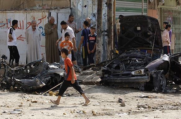 Iraqis inspect the aftermath of a car bomb attack at Baghdad`s mostly Shiite neighborhood of Husseiniyah, Iraq.