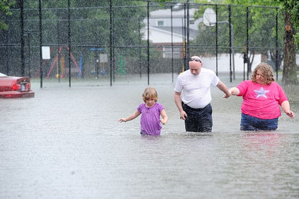 James Gregory and his daughters Autumn and Rayanna wade through water on Coventry Court in their east side apartment complex, Ashley Pointe, in Evansville, Ind. after they try to get back home because the roads were impassable.