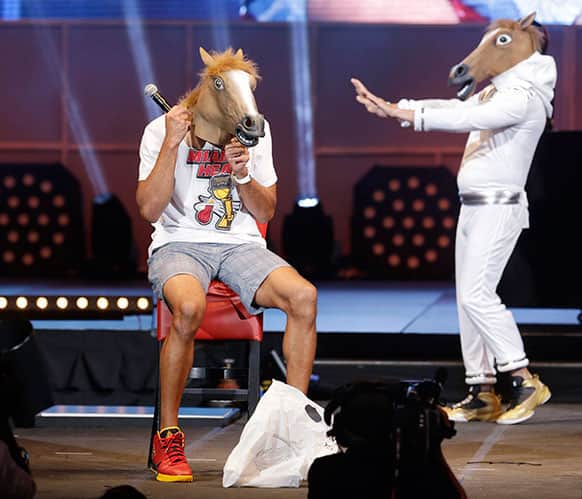 Miami Heat forward Shane Battier, foreground puts on a horse head mask as an unidentified person in a mask dances behind him, during a celebration for season ticket holders at the American Airlines Arena in Miami.