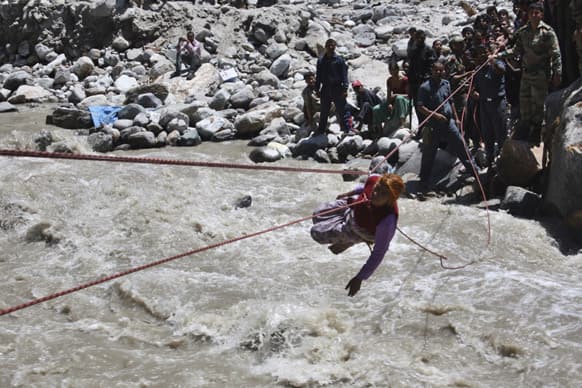 Army soldiers make a stranded pilgrim to cross over a river with the help of a rope near Hemkunsaheb.