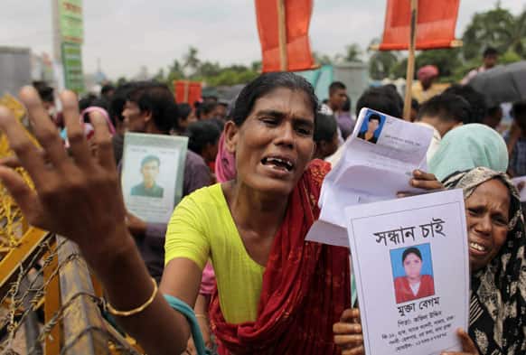 Bangladeshi women cry holding photographs of their missing relatives as they plead for help and demand compensation for the dead and missing workers of the garment factory building collapse, in Savar, near Dhaka.