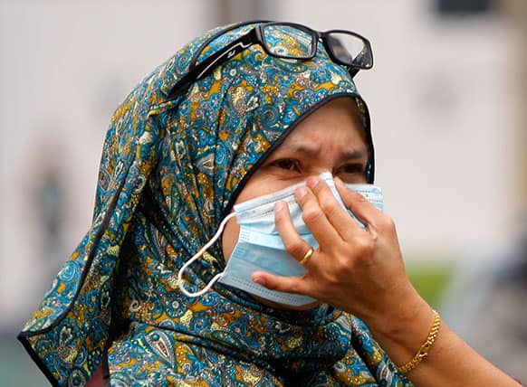 A woman covers herself with a face mask as she walks on a street in downtown Kuala Lumpur, Malaysia.