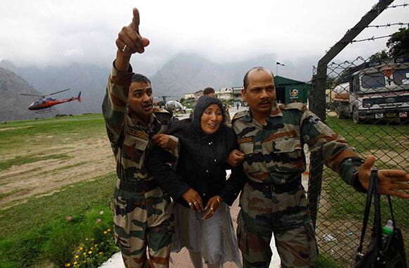 An injured pilgrim cries as army soldiers carry her after she was rescued from the higher reaches of mountains, at a makeshift helipad at Joshimath, in northern Indian state of Uttarakhand.
