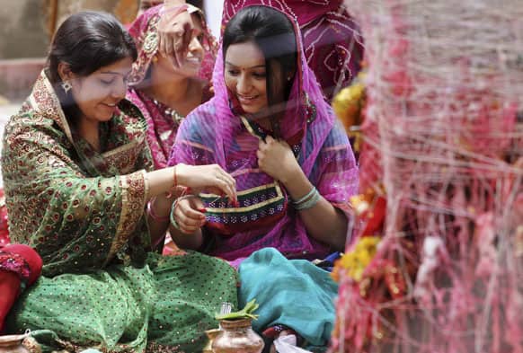 A married Hindu woman ties holy thread on another`s wrist during Hindu festival of Vat Savitri in Ahmadabad. Vat Savitri is celebrated on a full moon day where women tie cotton threads around a banyan tree and pray for the longevity of their husbands.