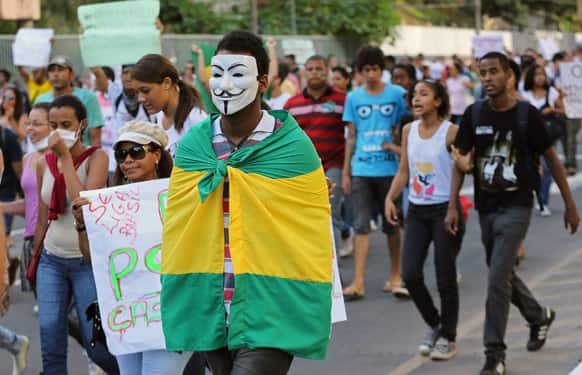 A masked demonstrator carries a Brazilian flag on his back near the Arena Fonte Nova stadium in Salvador, Brazil.