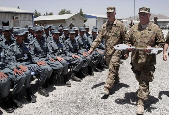 Afghan soldiers watch two US Army officer carry a giant symbolic key during the fifth phase of a transfer of authority ceremony of the police academy from NATO-led troops to Afghan security forces in Kabul, Afghanistan.