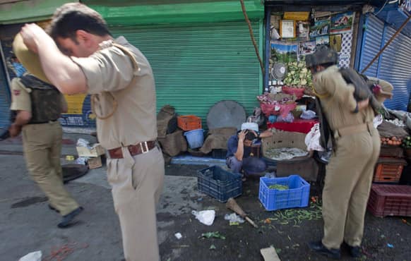 A Kashmiri shopkeeper reacts in fear as policemen arrive near the site of a shootout in Srinagar. A top police official said suspected militants have shot and killed two police officers in Kashmir.
