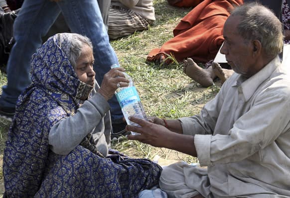 An elderly couple help each other to drink water before being evacuated from the upper reaches of mountains, in Gaurikund, Uttrakhand.