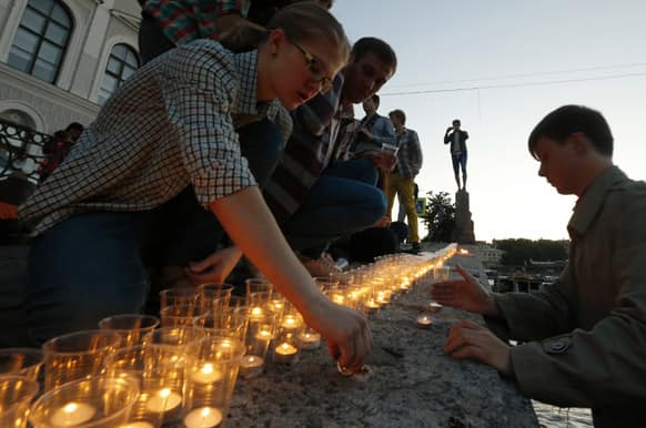Young people light candles at Fontanka River embankment near a monument for the WWII victims early morning, at the time the Nazi Germany attacked the Soviet Union 72 years ago, in St.Petersburg, Russia. People lighted 1,418 candles, the numbers of the days of the war.