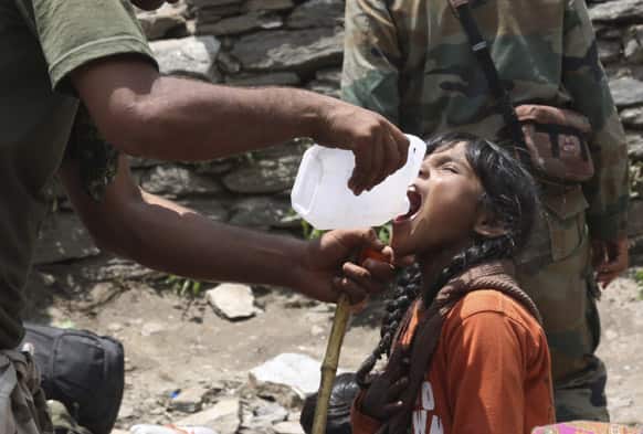 An Indian army soldier helps a young girl, affected by floods, drink water before evacuating her from the upper reaches of mountains, in Gaurikund, Uttrakhand.
