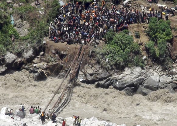 Indo-Tibetan Border Police (ITBP) personnel help stranded pilgrims on a makeshift bridge cross a stream of gushing floodwater at Govind Ghati, in Chamoli district, in Uttarakhand.