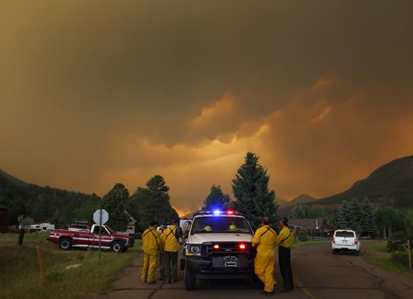 Firefighters stage in a residential area in South Fork, Colo., as they monitor a wildfire that burns west of town. The town was evacuated and US 160 that passes through it was closed.