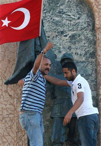 Man is helped down after he chained himself to the monument of Mustafa Kemal Ataturk, founder of modern Turkey during his protest at Taksim Square in, Istanbul.