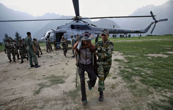 An Indian army soldier helps a flood affected man after being evacuated by a helicopter from the upper reaches of mountains in Joshimath.