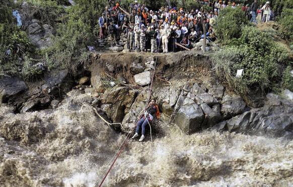 Indo-Tibetan Border Police (ITBP) use a rope to rescue stranded pilgrims cross a river swollen by flood waters at Govind Ghat, in Chamoli district, in northern Indian state of Uttarakhand.