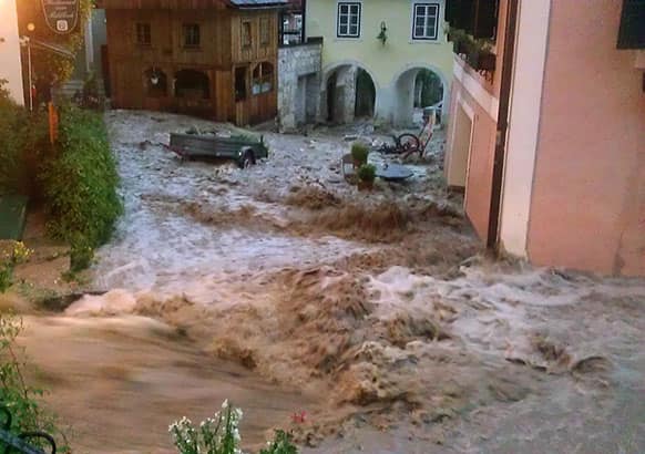 In this picture provided by Hallstatt.net flood rushes down a street in the village of Hallstatt, Austria.