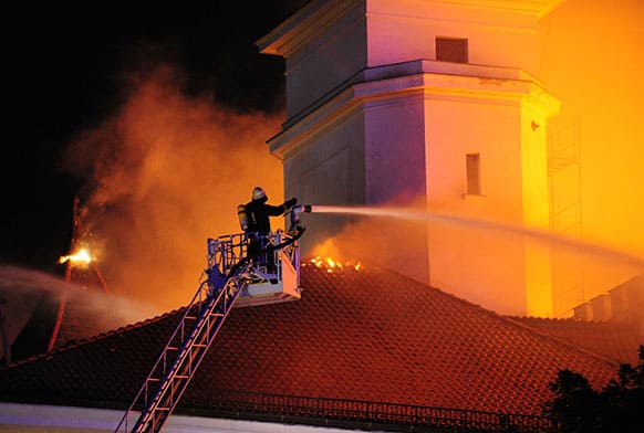 In this photo released by China`s Xinhua Agency, a firefighter tries to extinguish blaze on the roof of Riga Castle, Latvia.
