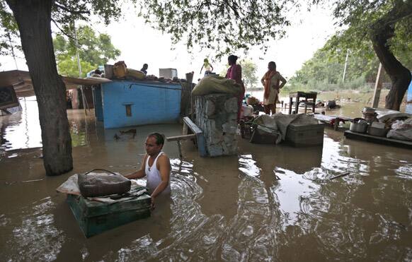 A man drags a trunk to higher ground after floodwaters inundated homes along the banks of the Yamuna River, in New Delhi.