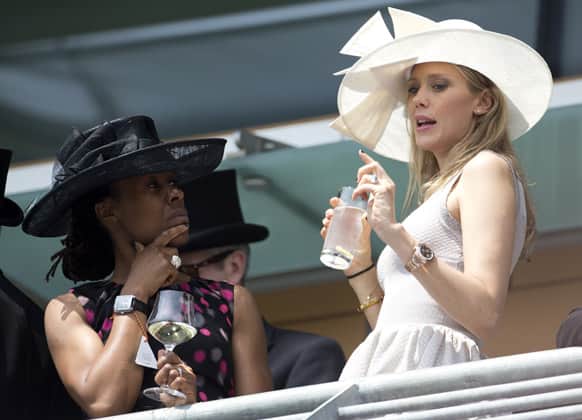 Two racegoers take in the view of the parade ring from a balcony in the royal enclosure as they wait for the arrival by carriage of Britain`s Queen Elizabeth II on the second day of the Royal Ascot horse race meeting in Ascot.