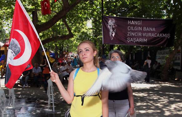 Turks, some of them holding national flags with images of Turkey`s founder Kemal Ataturk, stand in a silent protest in Kugulu Park in Ankara. After weeks of sometimes-violent confrontation with police, Turkish protesters have found a new form of resistance: standing still and silent.