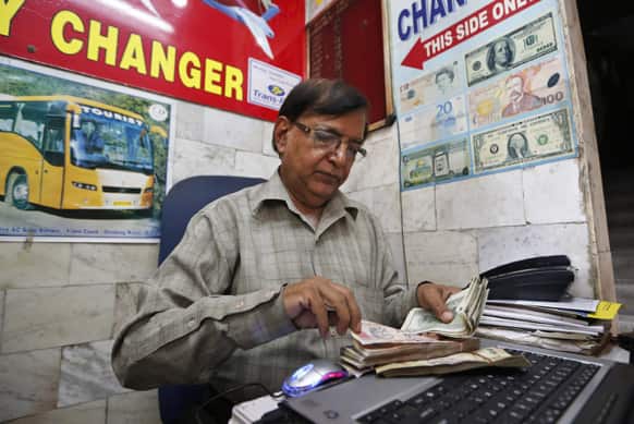 A money changer counts Indian rupees at his kiosk in New Delhi. Indian rupees touched its lifetime low of 59.93 to $1 on Thursday.