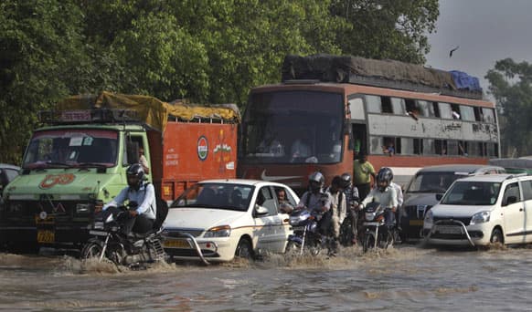 Commuters travel on a flooded road after a rise in the water levels of the Yamuna River in New Delhi. The latest rains have affected several states and the capital, New Delhi, where nearly 2,000 people were evacuated to government-run camps on higher ground.