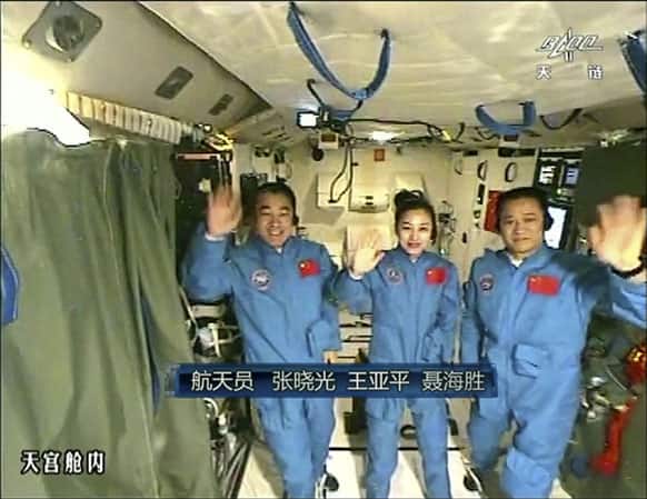 Chinese astronauts, Zhang Xiaoguang, Wang Yaping and Nie Haisheng waves during a live broadcast from onboard the Tiangong 1 prototype space station.