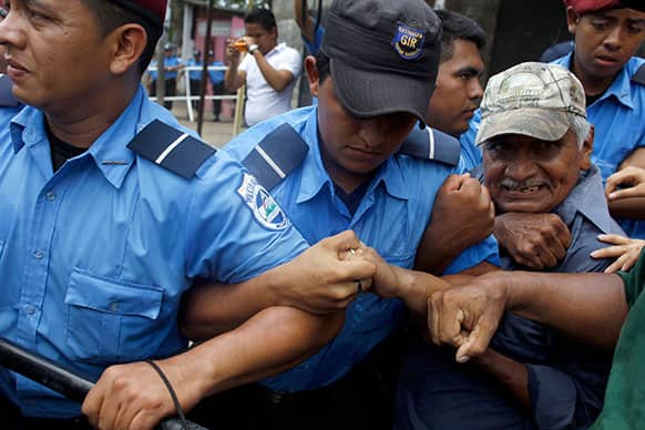 A members of the National Elderly Unit, right, clashs with police during a protest in front of the Social Security building to demand their pensions in Managua, Nicaragua.