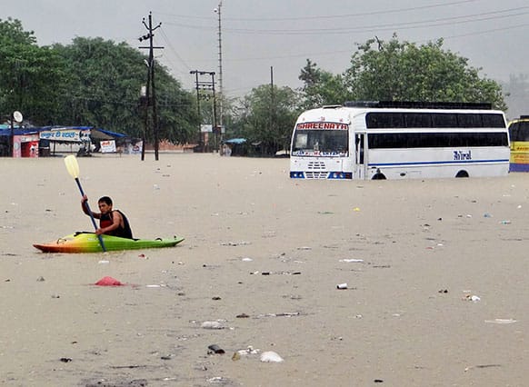 A man rows past a bus partly submerged in flood water in Rishikesh, in the northern Indian state of Uttarakhand.